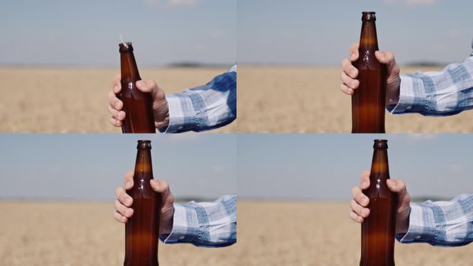 一名男子在麦田的背景下打开一瓶啤酒。慢动作视频