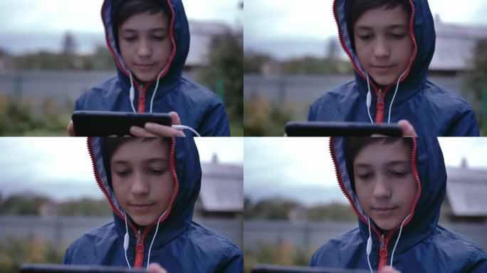 都市逃避主义:穿着卫衣的男孩在街上，沉迷于手机里的音乐