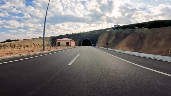 汽车进入高速公路隧道，黑暗笼罩着道路。视觉捕捉车辆视角下的车辆、隧道入口、高速公路进入隧道的过程，突