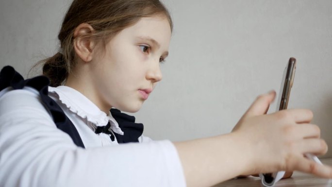 特写女学生在社交网络上和朋友聊天，玩在线游戏，在家用智能手机看视频。小女孩用手机发短信查邮件