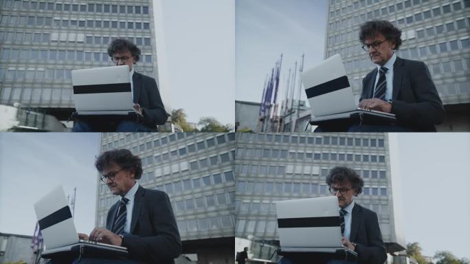 一个自信的白人成熟男性戴着眼镜使用笔记本电脑的肖像。在国际公司办公室以外的网上工作的成功经验的专业人