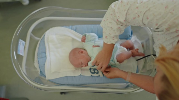 医管局母亲护理:婴儿躺在医院婴儿床时检查婴儿紧身衣