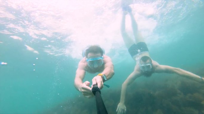 男性朋友带着面罩和通气管潜入海藻中