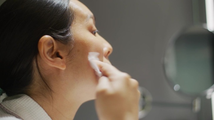 亚洲妇女在浴室用棉签洗脸