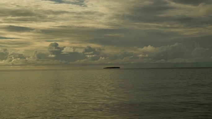 日落时平静的海浪。美丽的暴风雨前多云的天空为背景。