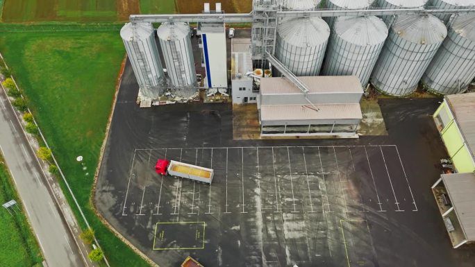 无人机拍摄到满载谷物的拖车在农场的筒仓间行驶
