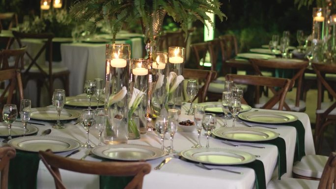 餐桌上装饰着自然的树叶，蜡烛和玻璃器皿的婚宴。