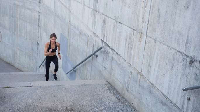 坚定的女运动员在城市楼梯上奔跑