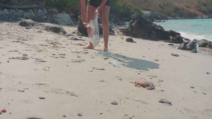年轻女子在海滩上捡垃圾