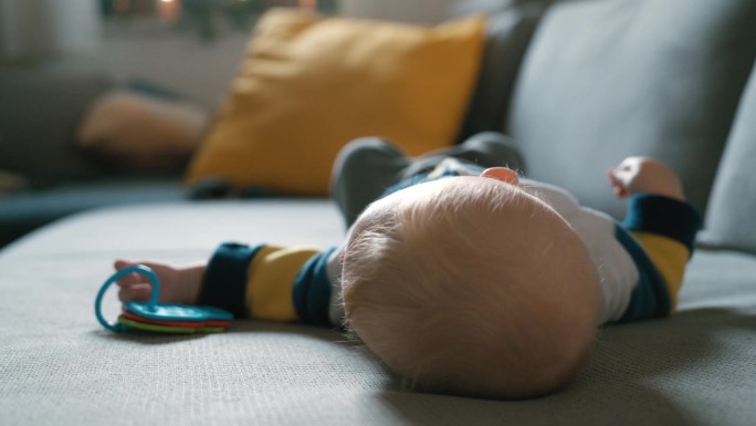 好奇的小男孩抱着玩具躺在沙发上
