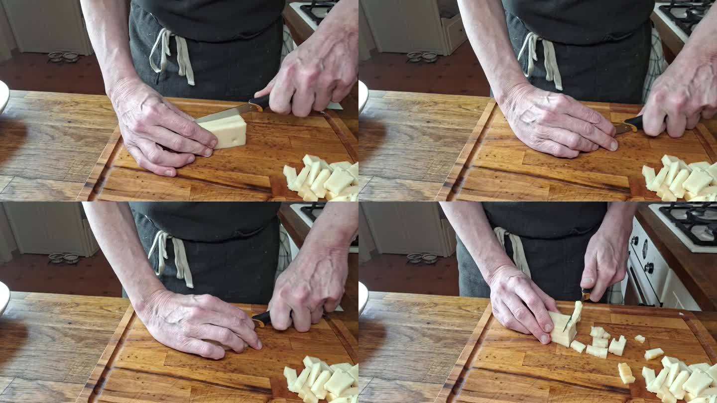 厨师把奶酪切成小方块。男人的手把奶酪切成方块。烹饪，烹饪和烹饪的概念。家庭厨房的录像。