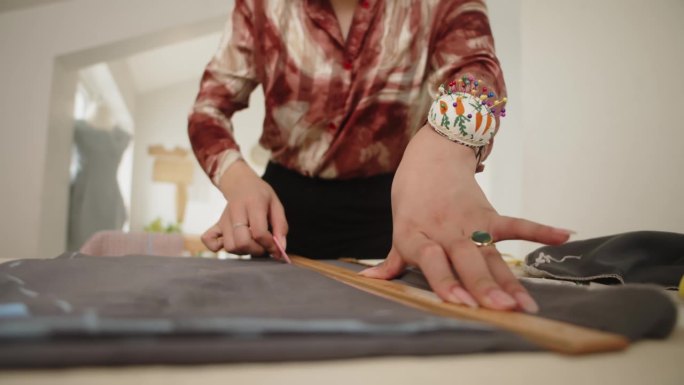 在缝纫工作室里，女人用粉笔在织物上做记号的手