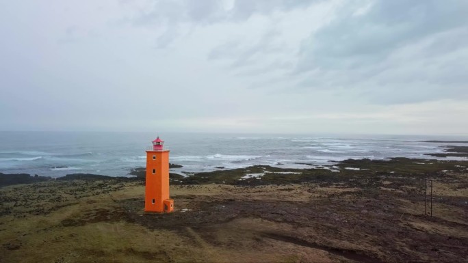 在冰岛，橙色的灯塔与岩石嶙峋、喜怒无常的海岸线形成鲜明对比。空中轨道。