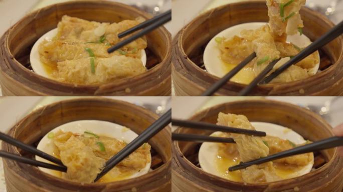 点心和筷子夹蘸酱蒸豆腐皮卷的特写