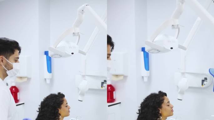 垂直视频的一个年轻的拉丁妇女病人冲洗她的口腔在牙槽，而她的牙医正在等待继续程序。