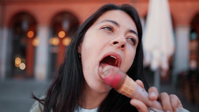 享用冰淇淋冰淇淋甜筒的女人特写脸。30多岁的女性在欧洲吃甜点
