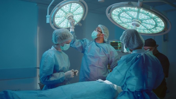 一位外科医生正在修理一个大灯，并调整它，以便他的手术有完美的照明，护士们站在他周围。拍摄于ARRI