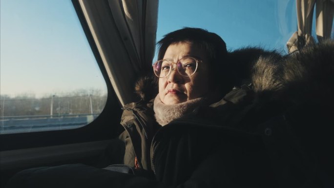 一名亚裔中国妇女坐在公交车里看着窗外