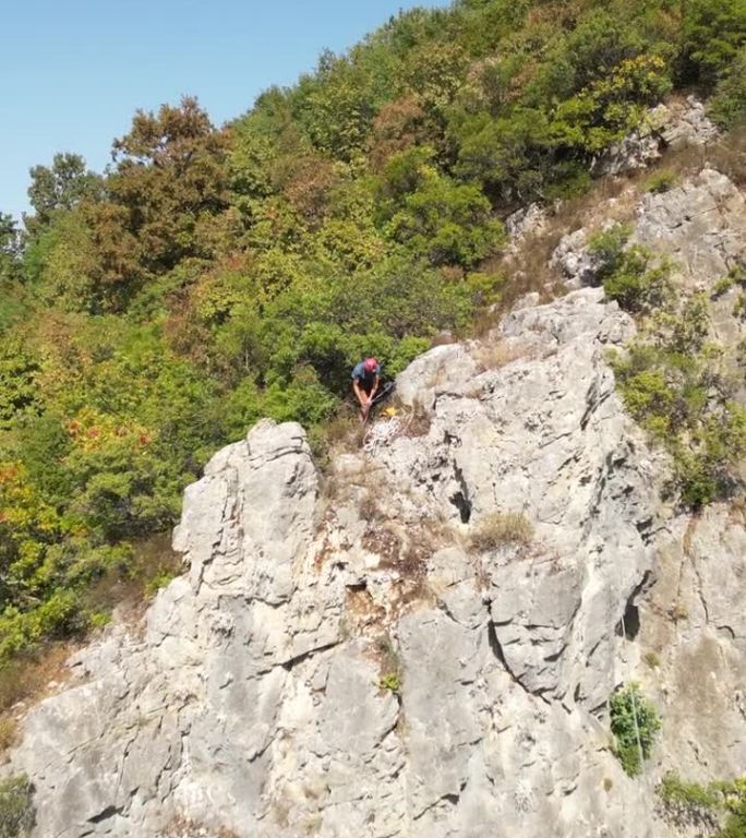 戴着红色安全帽的攀登者在岩石顶部准备攀爬绳，准备下山。