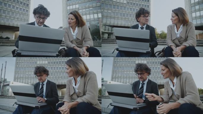 商务人士在城市中使用笔记本电脑交谈