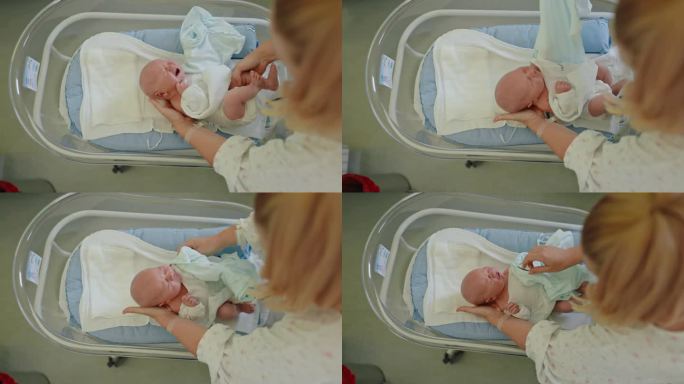 医管局母亲的护理:为躺在医院婴儿床上的婴儿穿紧身衣