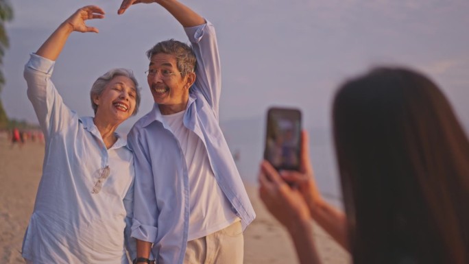 老夫妇一家在海滩上与当地导游一起享受，而她用智能手机拍照。