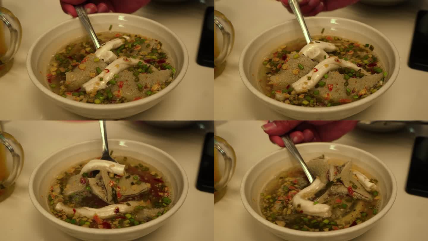 一只手正在用新鲜的汤汁搅拌一碗由骨髓、牛肚和肠子组成的内脏汤。