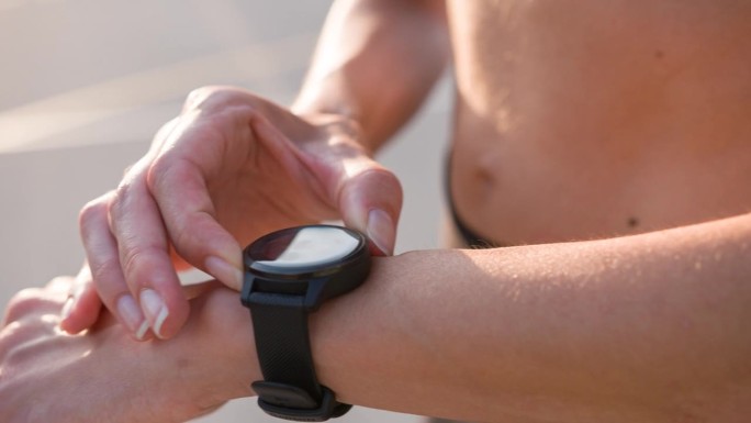 活跃的女性在户外跑步，用智能手表健身应用跟踪进度