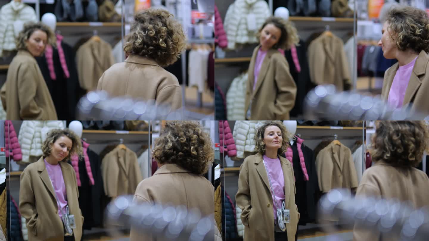 年轻女子在服装店试穿时髦的大衣。时尚的购物者在精品店的镜子前检查她选择的衣服。购物狂喜欢在打折季买衣