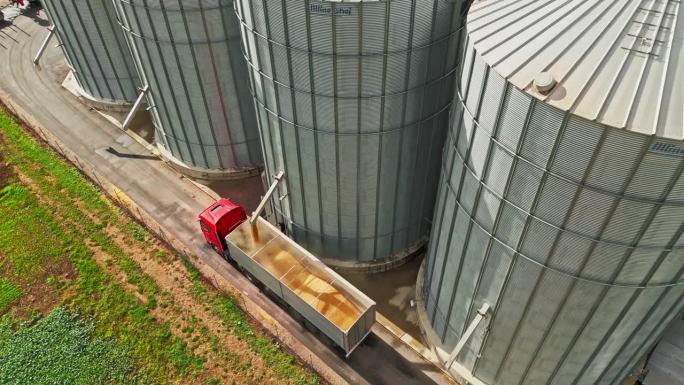 在阳光农场，无人机拍摄了装满谷物的筒仓卡车