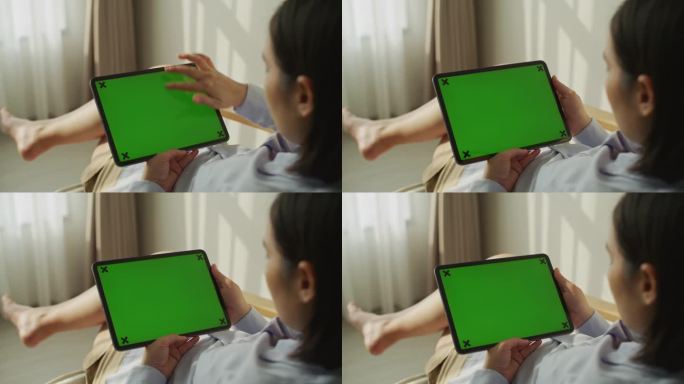 一名亚洲女性使用绿色屏幕的平板电脑
