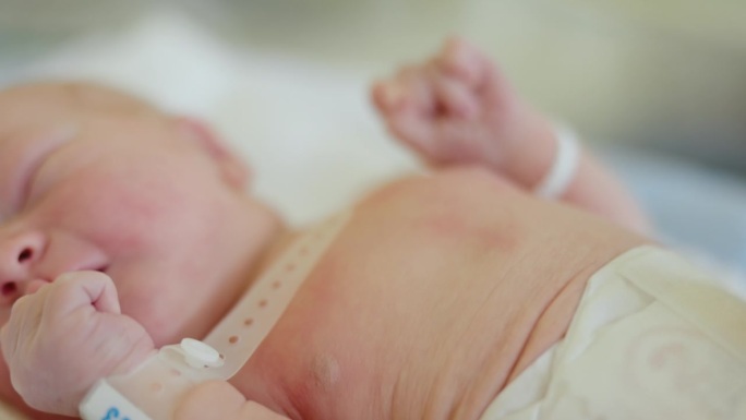 MS新生儿的纯真:一个新生儿的小手休息在医院婴儿床在产科病房