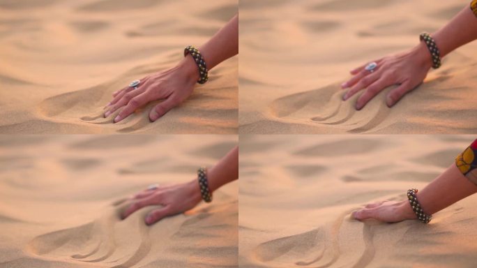 印度女孩在沙漠中手玩沙子的特写。在印度拉贾斯坦邦斋沙默尔的塔尔沙漠的Khuri沙丘上，女性的手在金色
