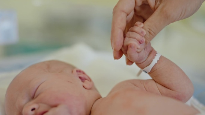 CU连接的心:母亲的手拥抱新生婴儿的小手指