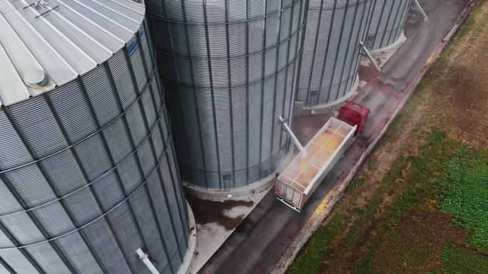 慢动作无人机拍摄农村农场的粮仓装满拖车卡车