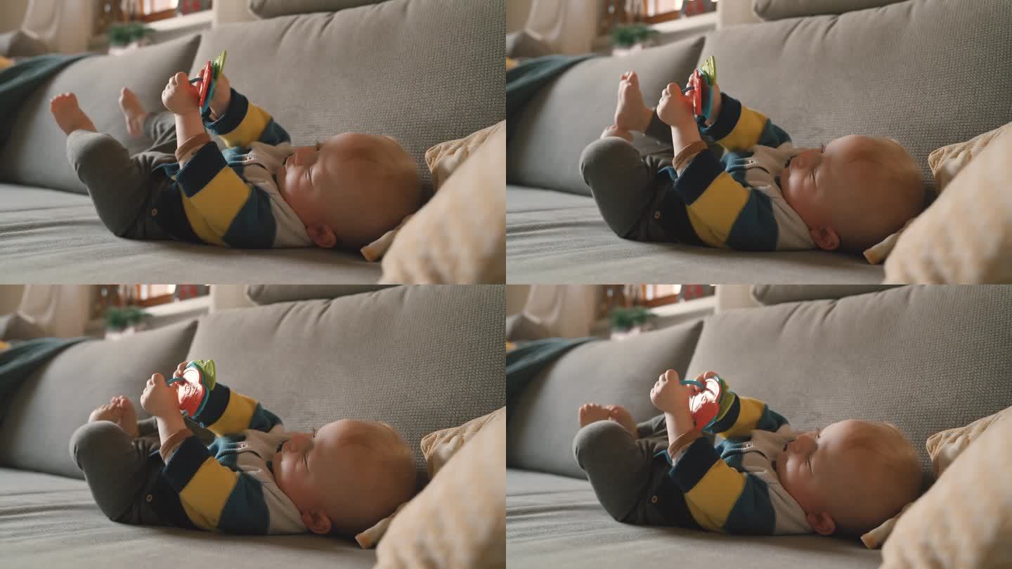 小男孩躺在家里的沙发上玩玩具