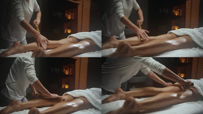 女按摩师在水疗中心对女人的腿进行按摩木材疗法