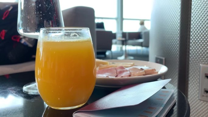 在机场的贵宾休息室享受豪华小吃熟食店:橙汁、苏打水和一桌火腿和各种奶酪。