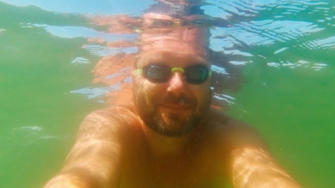 一名男子戴着泳镜拍摄自己在水下游泳的过程
