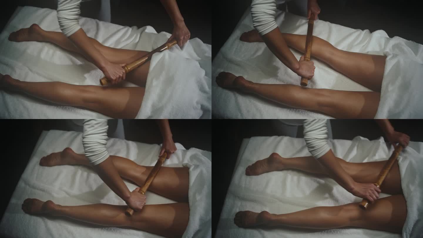 按摩师在健康水疗中心对女性的腿进行木材疗法