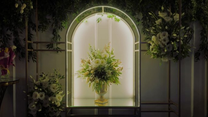 豪华的白花装饰，安排在一个单一的花束在一个黄金花瓶设置在一个发光的拱廊内