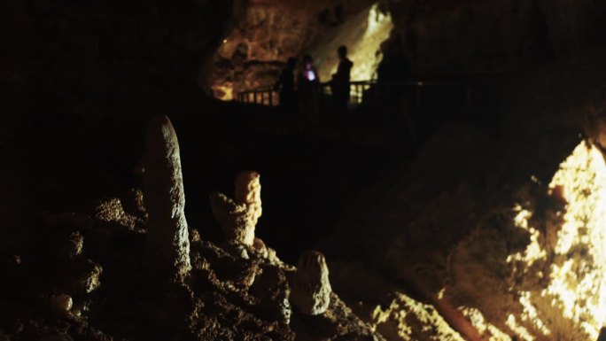 一群游客走过洞穴里桥上的石笋