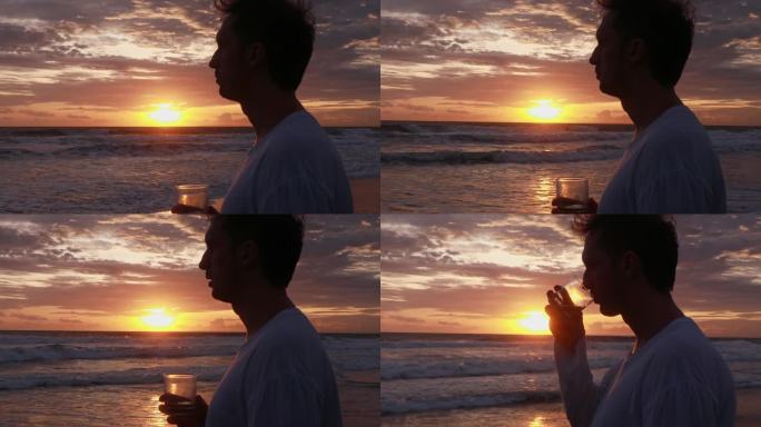 夕阳下海边，一个手里拿着玻璃杯的年轻人的侧面照