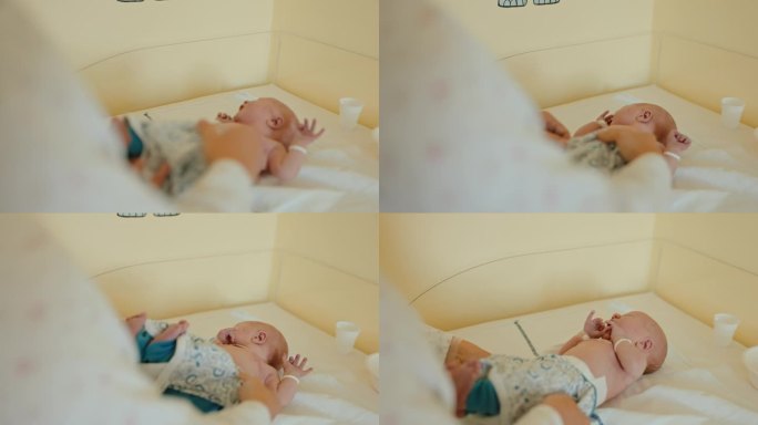 MS母亲的护理:给躺在医院婴儿床上的婴儿穿紧身衣