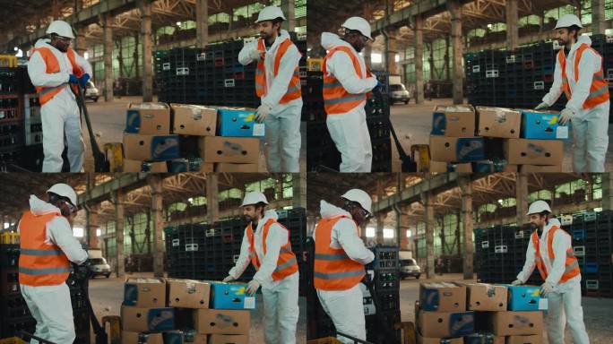 一名身穿白色制服的黑人男子和一名留着胡子、身穿橙色背心的同事正在垃圾回收厂的玻璃垃圾分类箱附近，试图