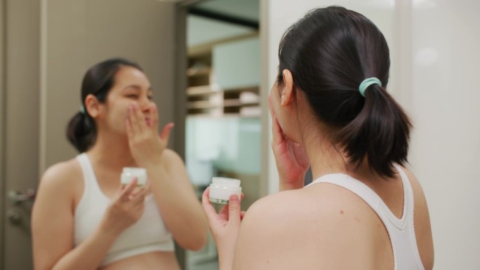 亚洲年轻女子在脸上涂抹润肤霜