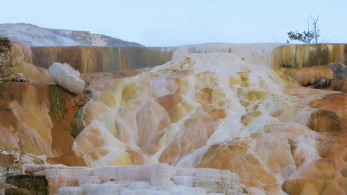 一群棕色和白色的岩石，背景是一座山，黄石国家公园
