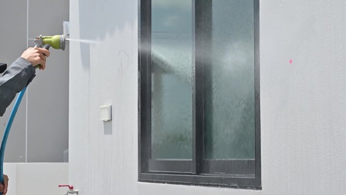 工程师使用软管喷水测试窗户泄漏。上门检查的概念。