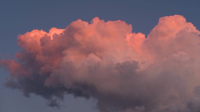 夕阳下，蓝蓝的天空上飘着鲜艳的橘红色蓬松的云，变化着形状，变换着造型