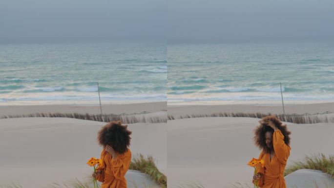 女人走在沙滩黄昏与橙色的花垂直。捧花女孩